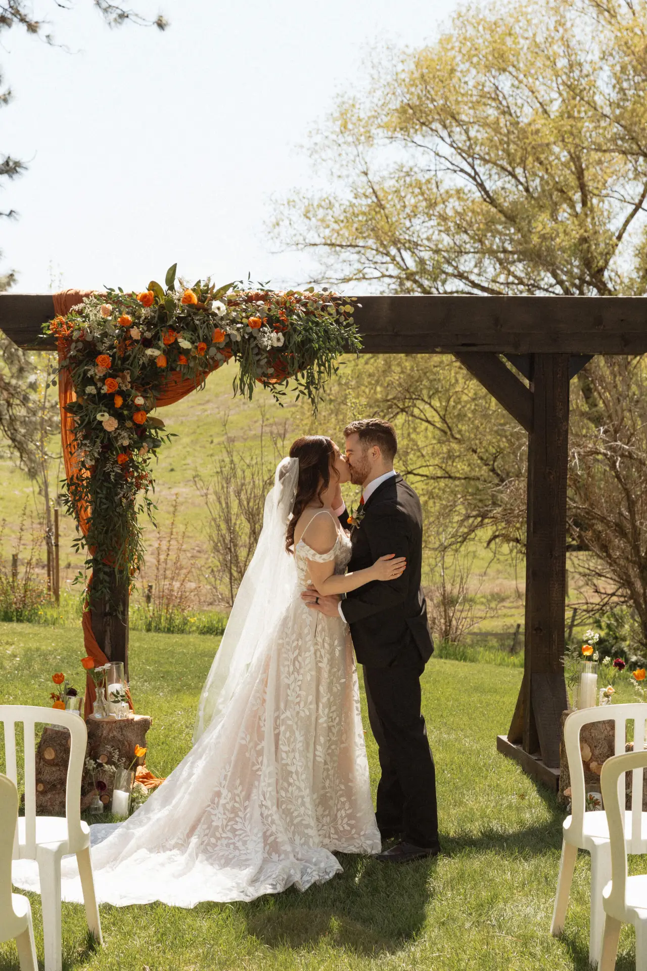 Bride and groom sharing their first kiss under a floral wedding arbor at Barn Owl Venue in Valleyford, Washington