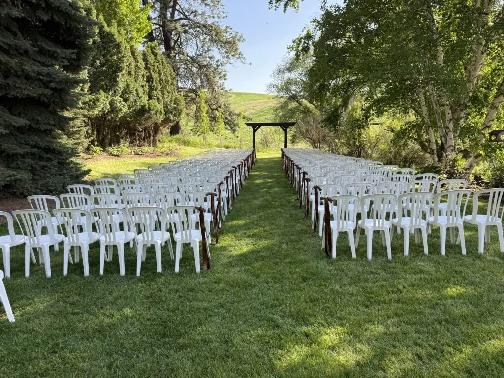 Outdoor wedding ceremony lawn at Barn Owl Venue with rows of white chairs and a wooden arbor