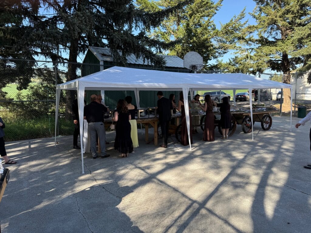 Tent-covered buffet setup on the tennis court for a wedding at Barn Owl Venue