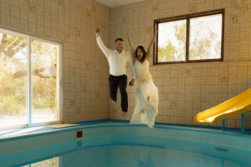 Wedding couple jumping into the indoor pool during a styled shoot at Barn Owl Venue
