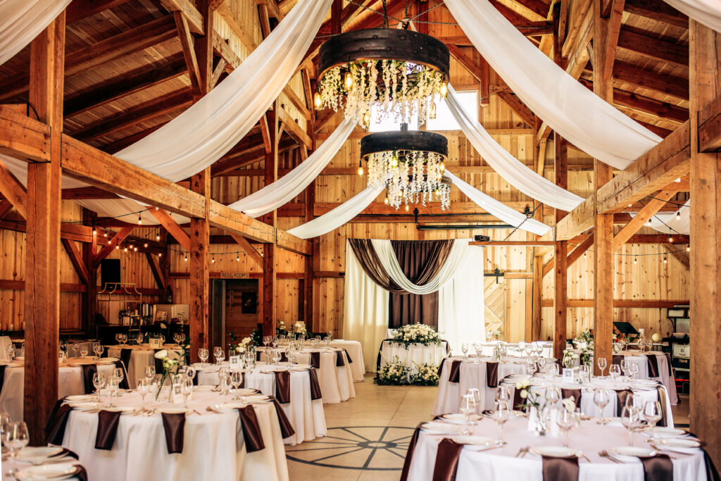 Wedding reception setup inside the barn at Barn Owl Venue with draped fabric and decorated tables